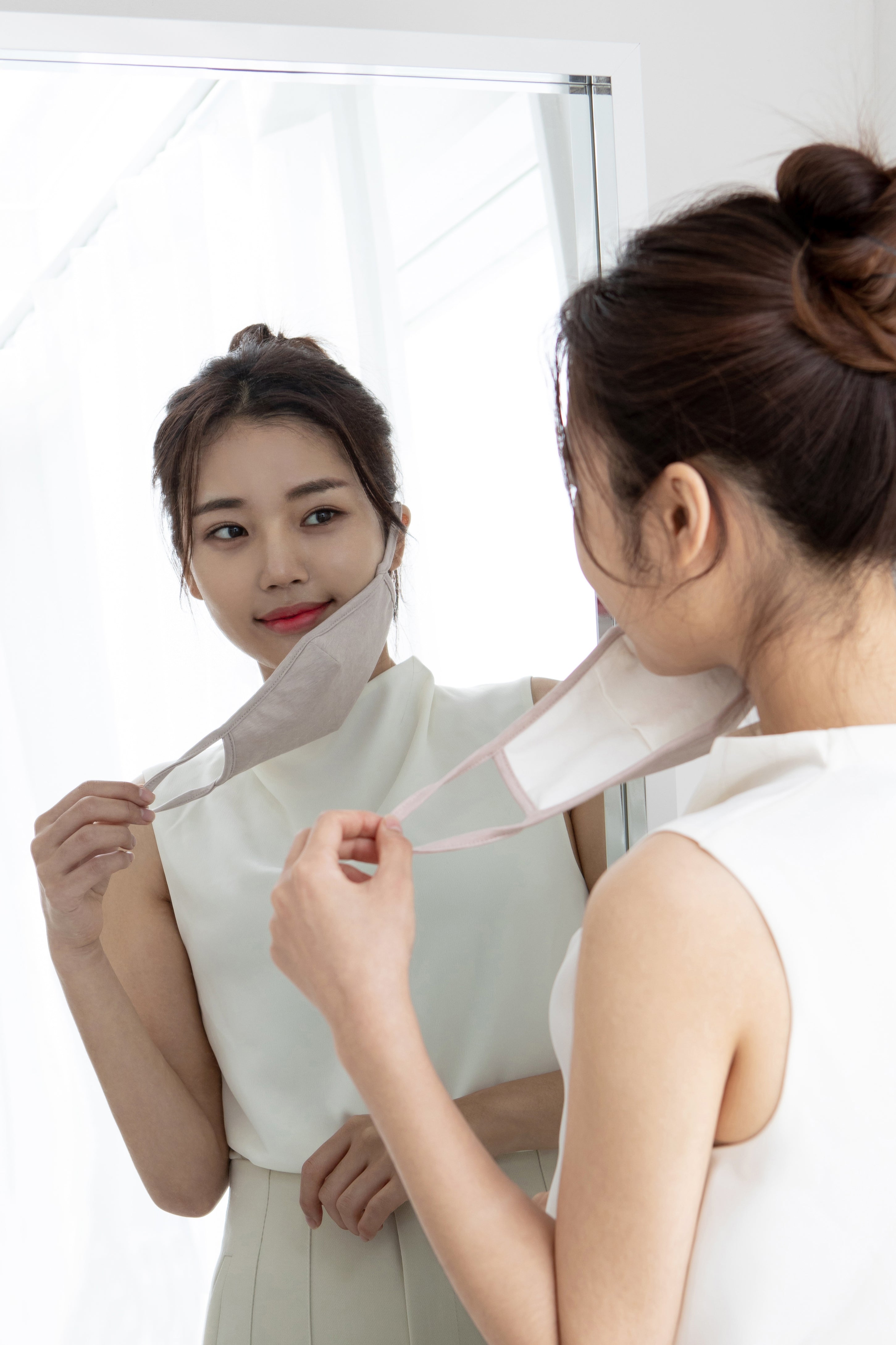 An Asian woman using mask and looking at the mirror