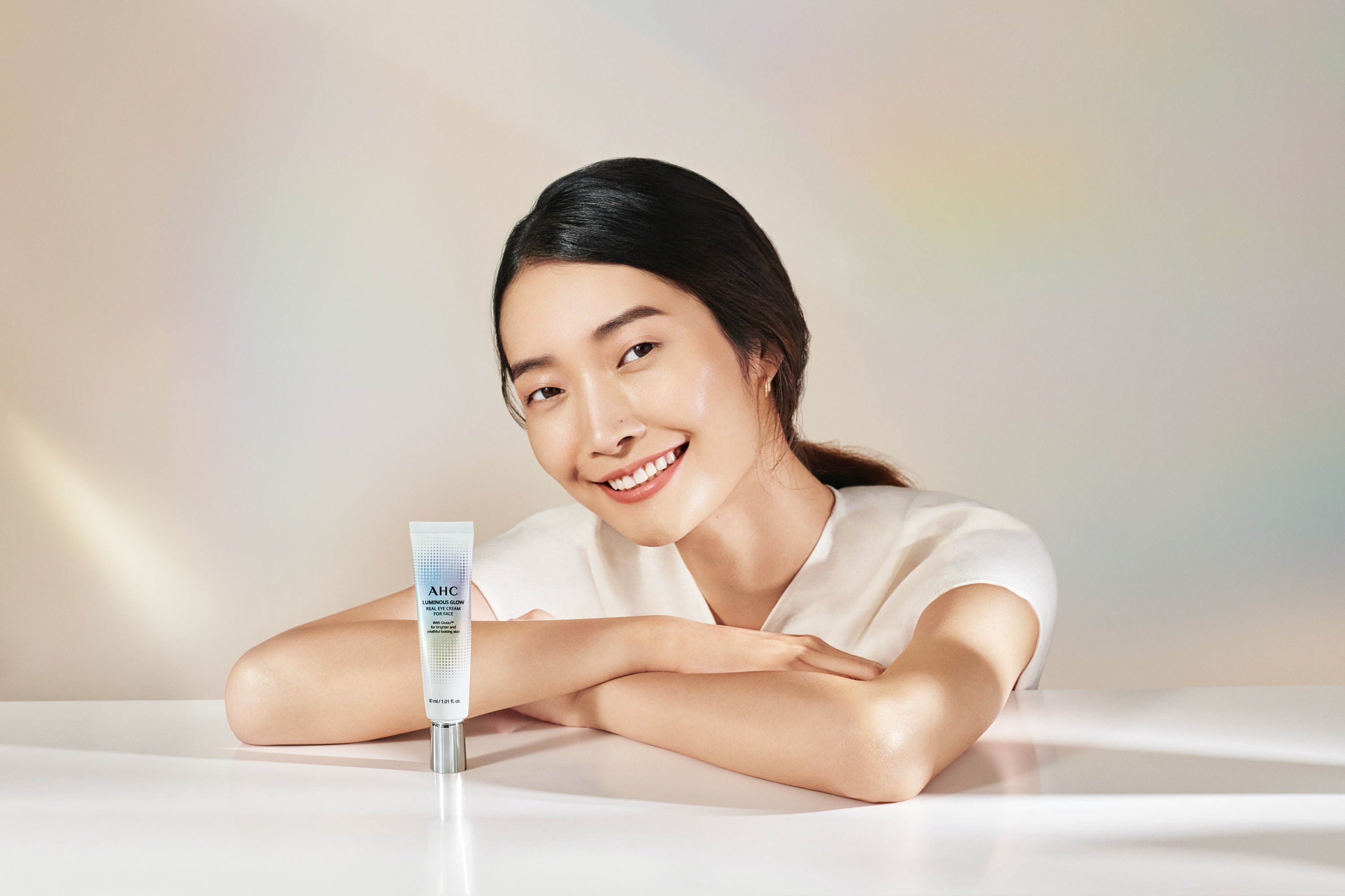 An Asian woman smiling and looking at the camera with AHC Luminous Glow Real Eye Cream for Face