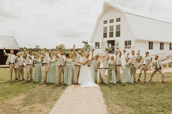 Bridal Party excitedly cheering in front of white barn and countryside setting.