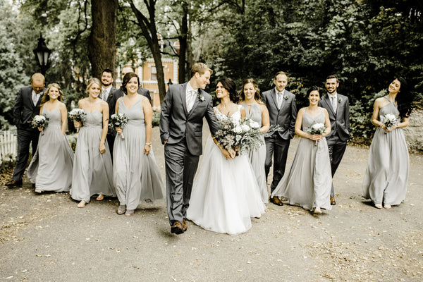 Bridal Party strolling down a tree covered sidewalk. Groomsmen are wearing grey suits and ties. 