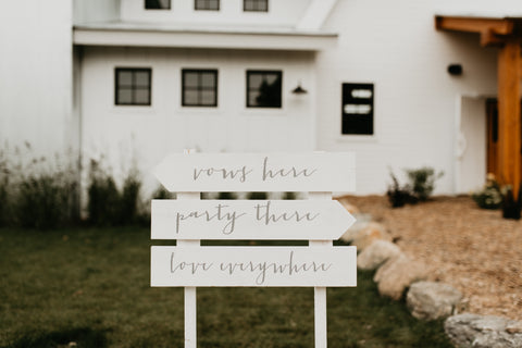 Wooden sign with various arrows, stating: " Vow Here", "Party There", "Love Everywhere"