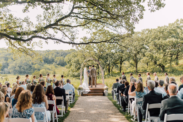 Bride and Groom underneath a dainty pergola during their ceremony in the picturesque countryside.  Bridesmaids are wearing Kennedy Blue dresses.