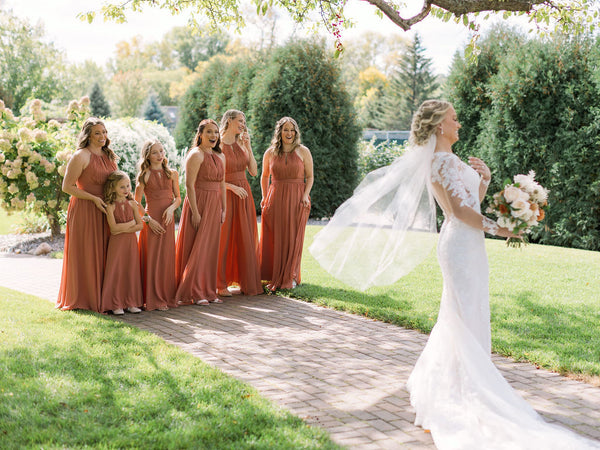 Bride showing off her dress in front of her bridesmaids for their first look.