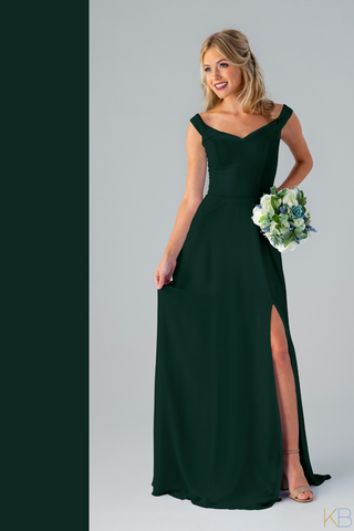 Model in Kennedy Blue Bridesmaid Dress "Haley" in 'Forest Green'. Elegant dress with an off-the-shoulder sleeves and long skirt with a side slit.