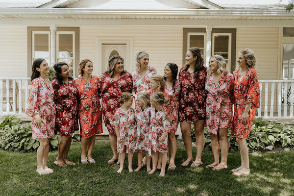 Bride and Bridesmaids gathered outside wearing an arrangement of Kennedy Blue Floral Bridesmaid Robes as they smile and laugh together. 