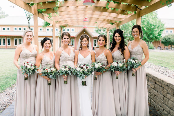 Bride and Bridesmaids standing beside each other, standing in front of a wooden arch.