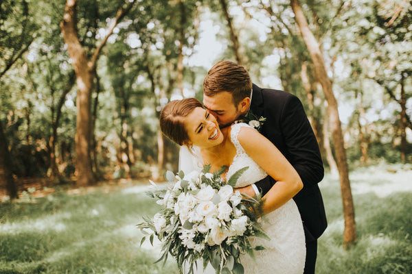 Wedding photo of groom and bride with a luscious greenery background.