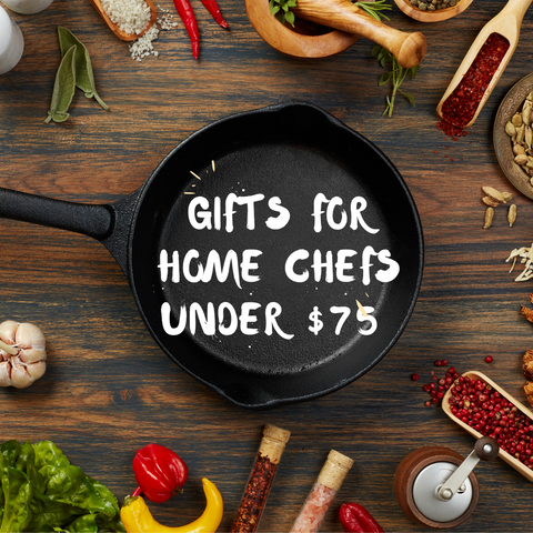 Words in white "GIfts for Home Chefs under $75" overlayed on a black cast iron pan on a wood surface with cooking ingredients scattered around