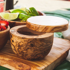 Olive wood salt cellar with the lid open on a patio table