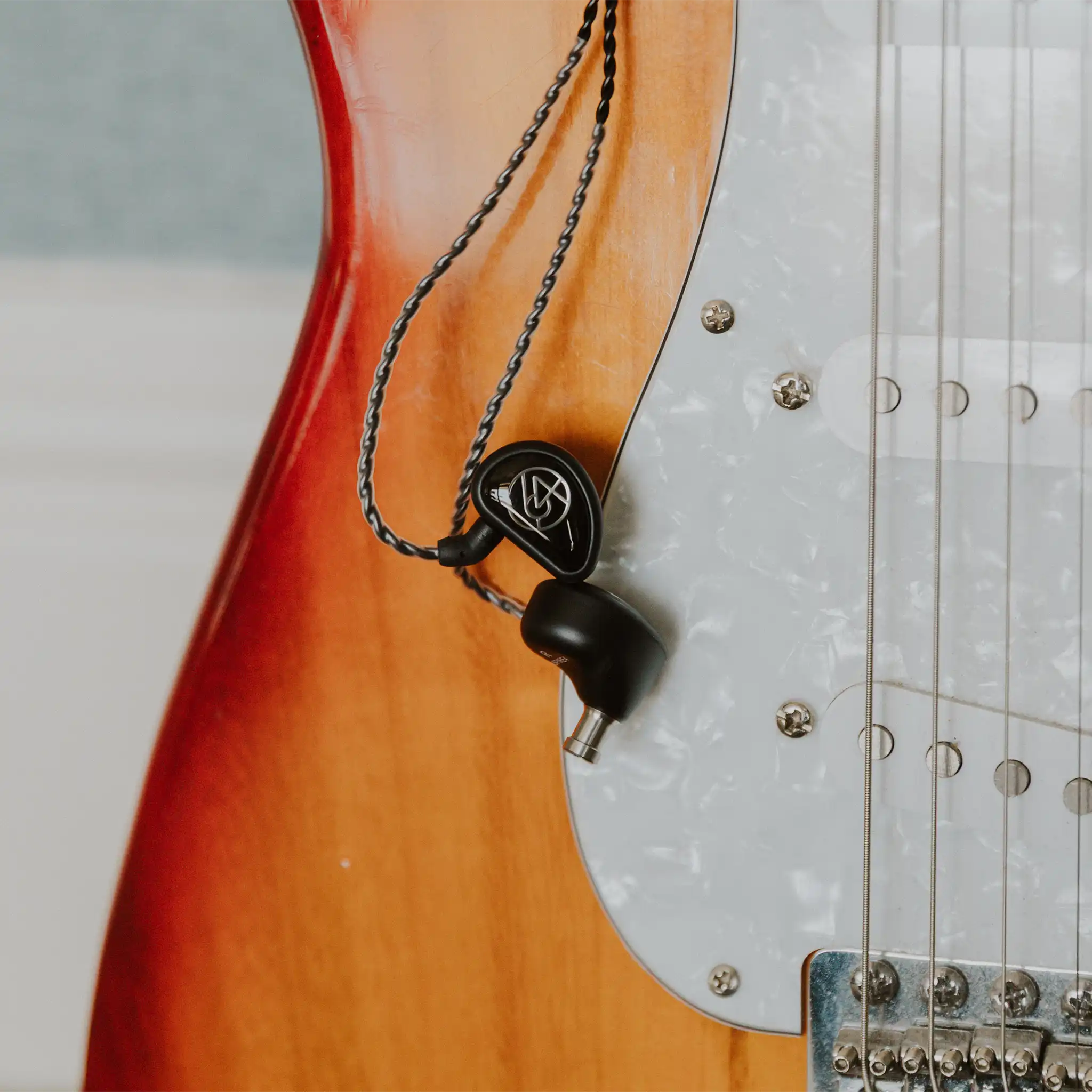 64 Audio Aspire 4 IEMs hanging from top of electric guitar