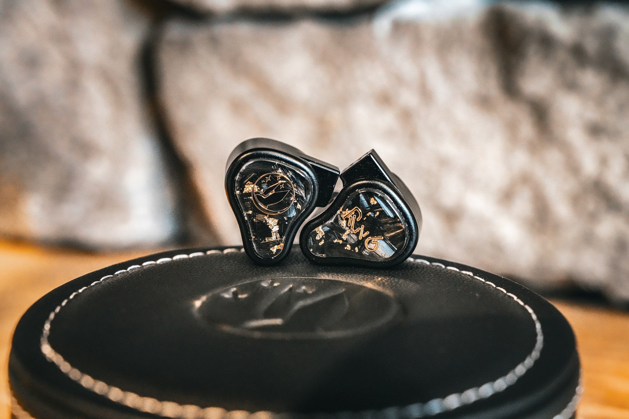 FiR Audio Radon 6 on top of its leather case resting on a wooden table with a stone wall in the background from the Bloom Audio gallery