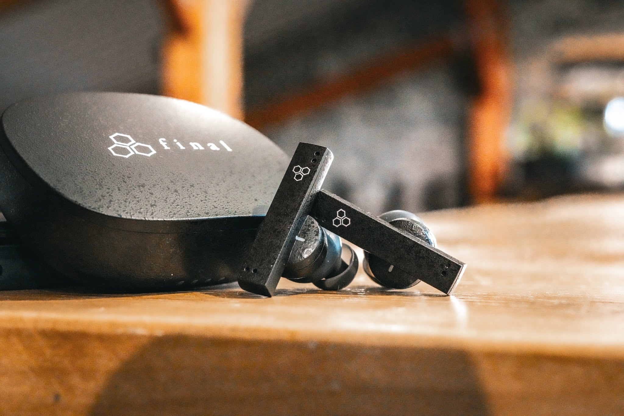 Final Audio ZE8000 next to their case on a wooden table with a stone wall and wood pillars in the background from the Bloom Audio gallery