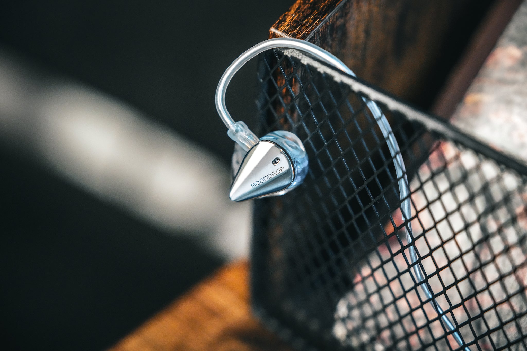 dramatic single Moondrop Blessing 3 earphone hanging from attached stock cable