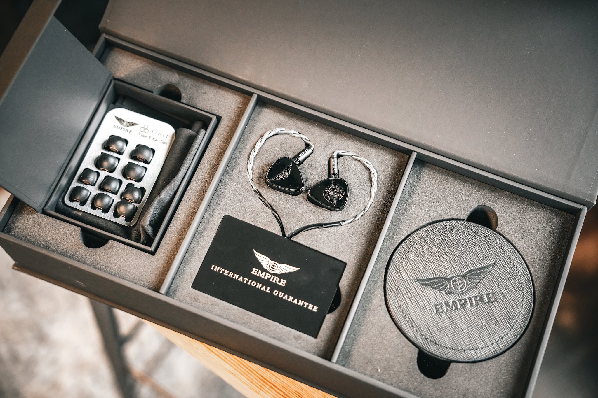 Empire Ears Raven black earphones inserted into open retail package with all accessories from Bloom Audio gallery