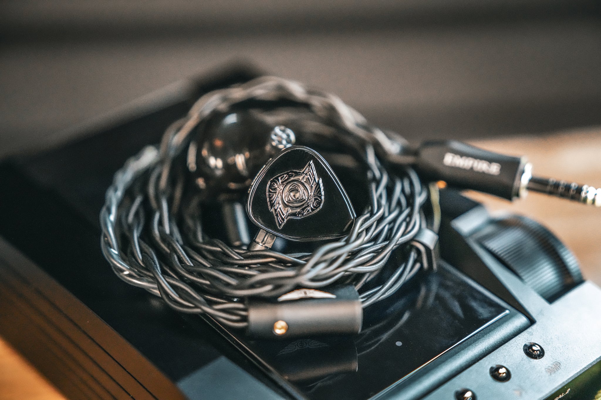 Empire Ears Raven black earphones with attached coiled stock cable on top of Astell Kern ACRO CA1000T DAP from Bloom Audio gallery