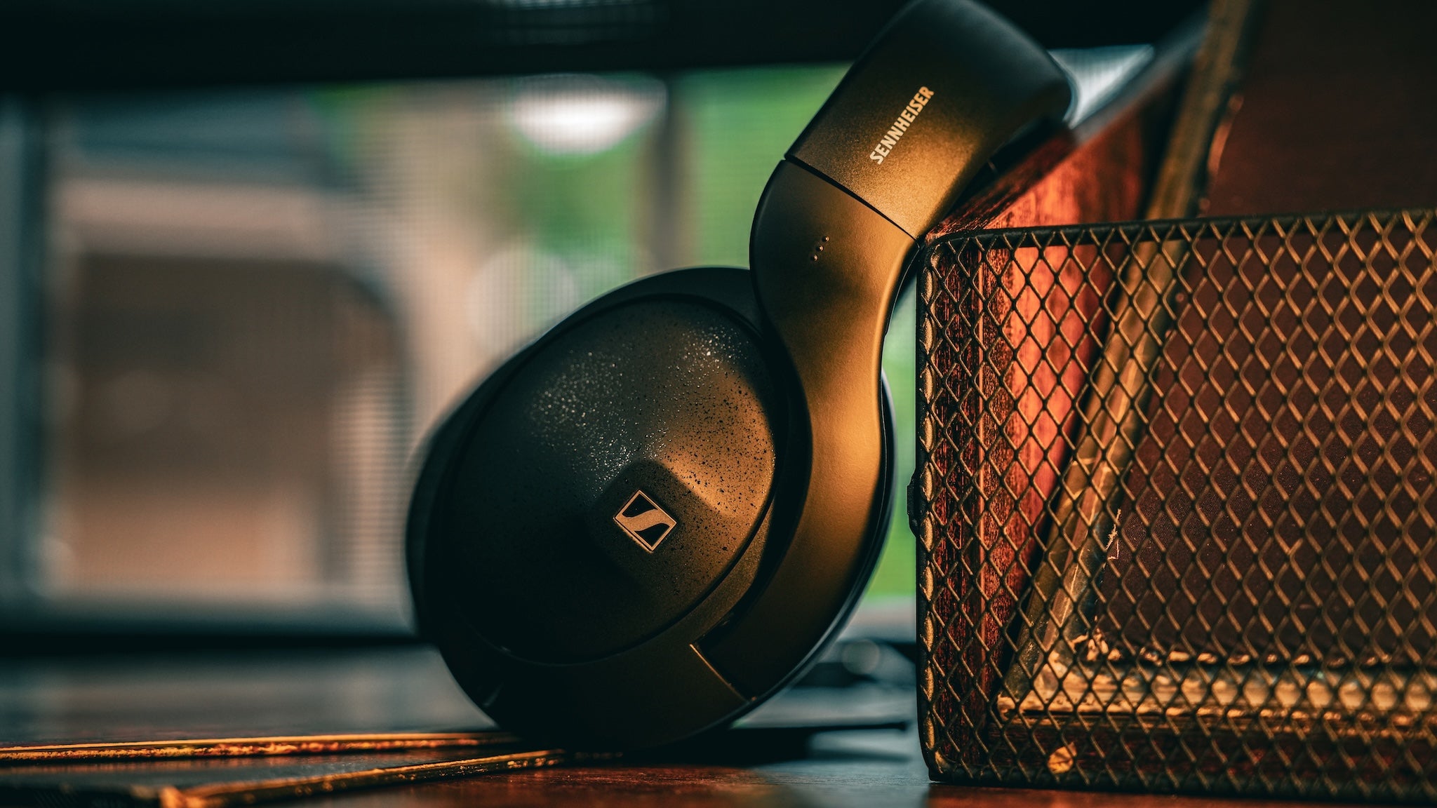 Sennheiser 620S leaning on a vinyl record organizer on a wooden desk with vinyl records below the headphone.