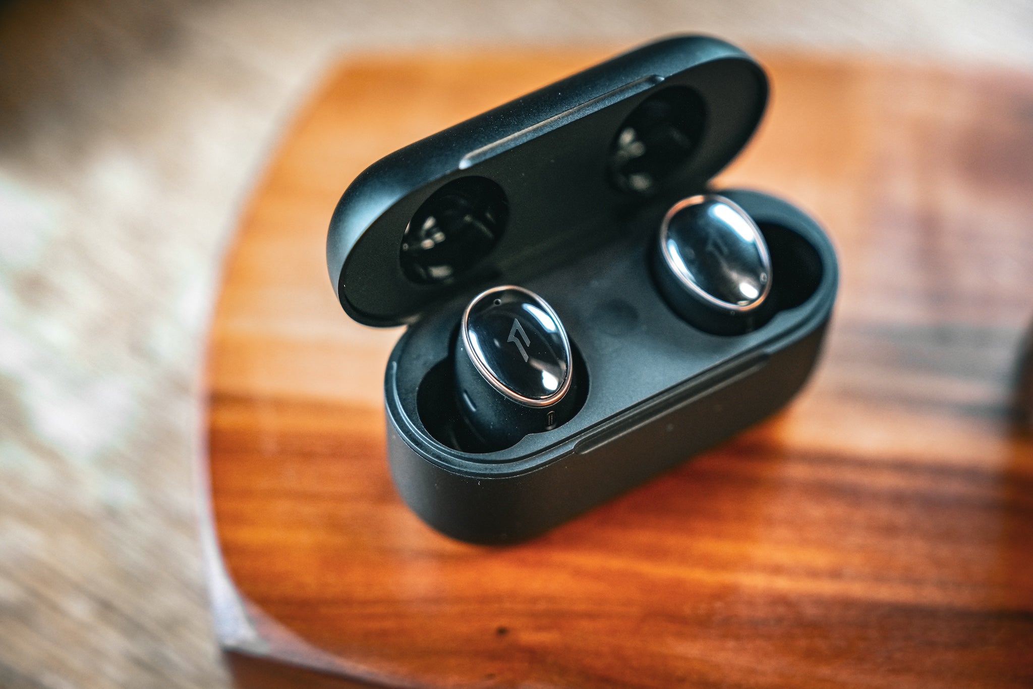 1More Evo earbuds in their case on a wooden headphone stand from the Bloom Audio gallery