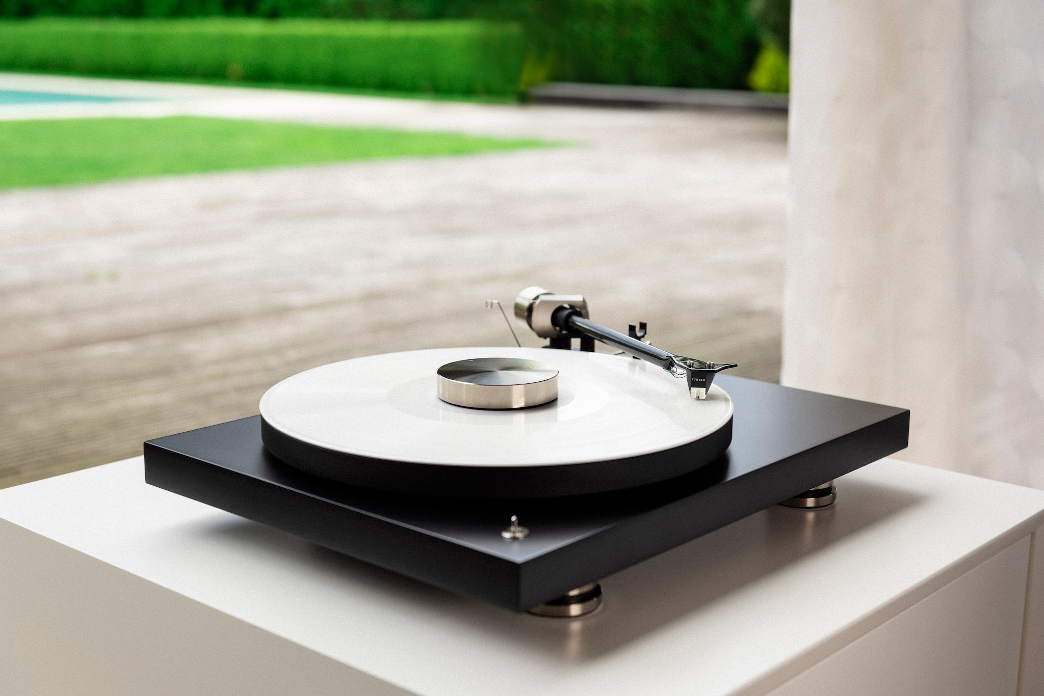 Pro-Ject Debut PRO 3 quarter on white cabinet overlooking manicured garden