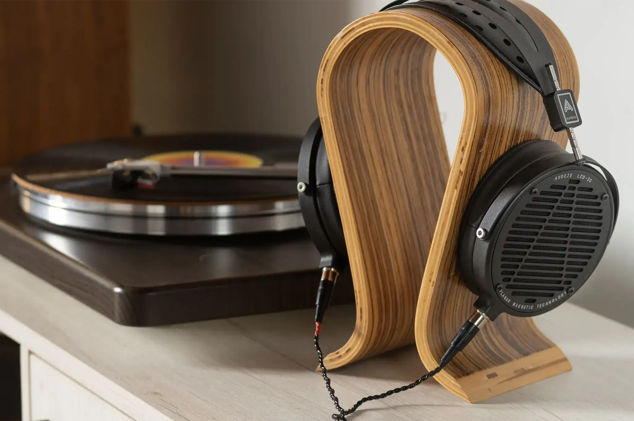 Audeze LCD-2 Classic headphones sitting on wooden stand on white wooden desk with record player