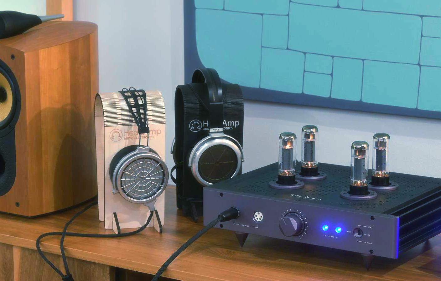 HeadAmp Blue Hawaii SE on wood desk with attached headphones on stands