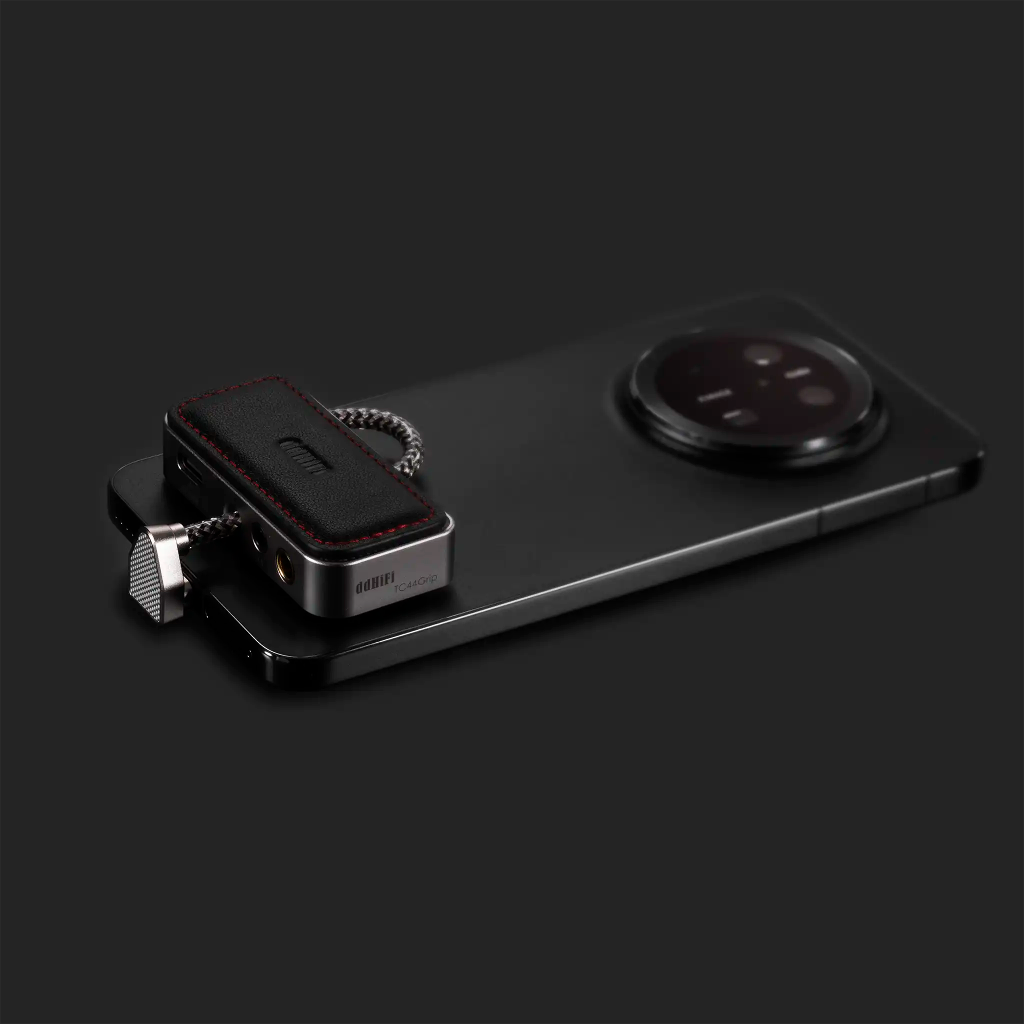 ddHiFi TC44Grip DAC dongle attached to black phone sitting left side view with attraction pad and black decorative pad on black background