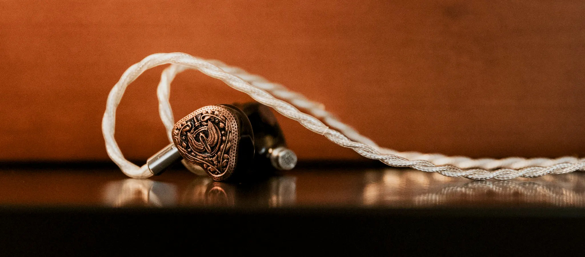 FlipEars Aegis earphones face forward on black metal table with attached stock cable