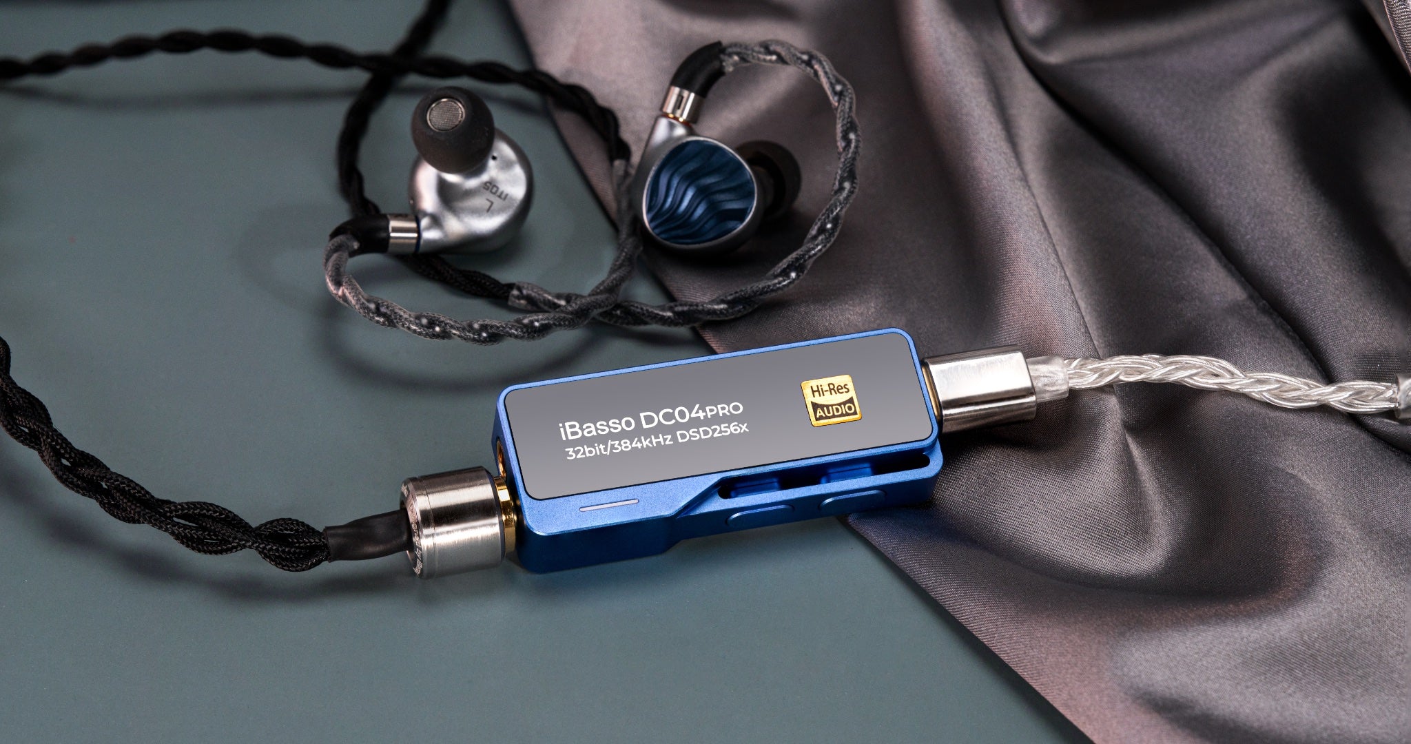 iBasso DC04 Pro blue DAC with attached earphones over silk fabric highlighting premium finish