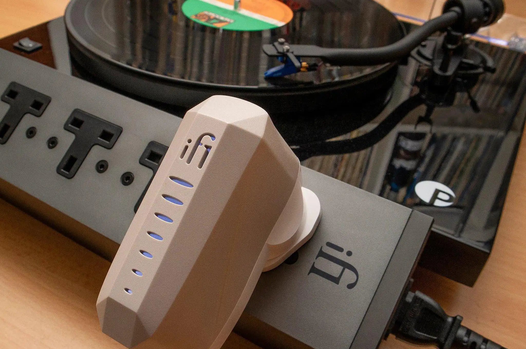 iFi iPower X power supply plugged into ifi power strip sitting on wooden table with record player