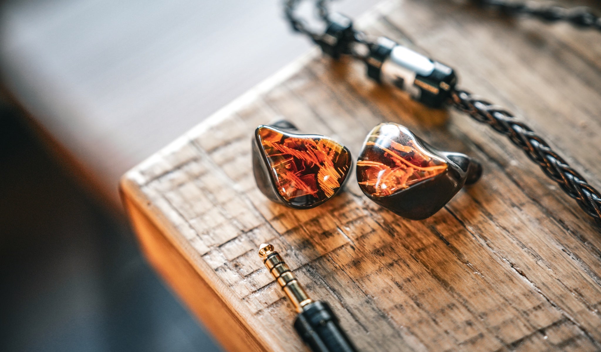 Noble Audio Spartacus IEMs with detached stock cable on wood block table from Bloom gallery