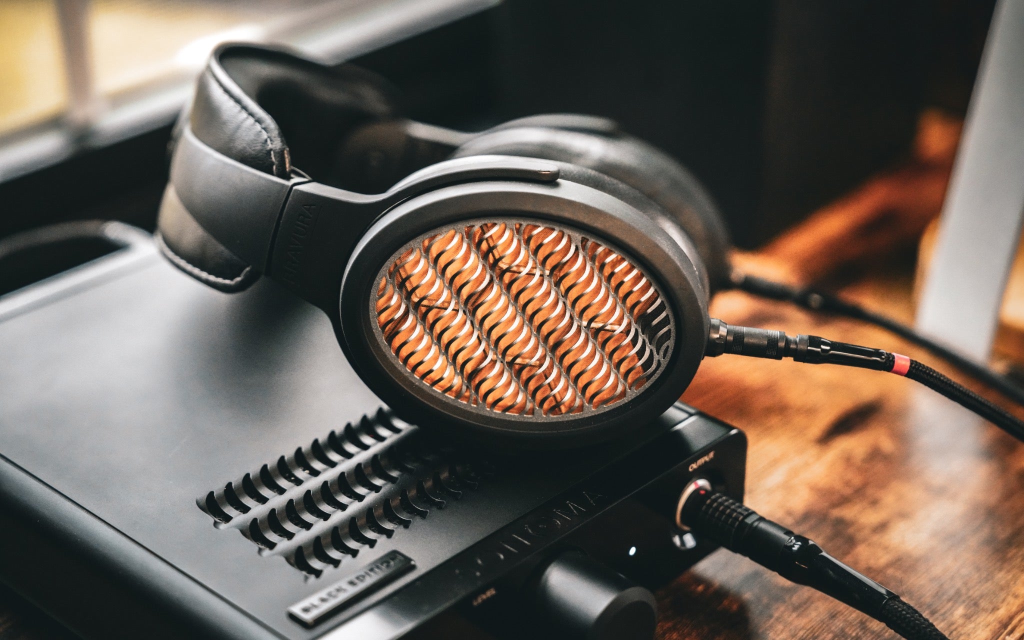 Warwick Bravura headphones resting on and connected to Sonoma amp on wood desk