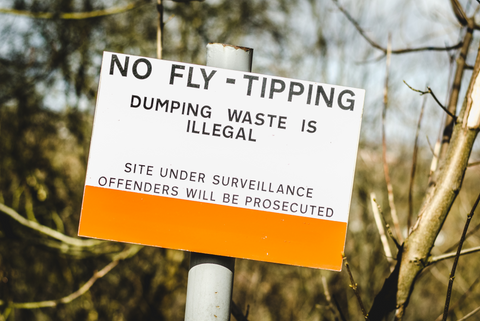 White and orange sign with 'No Fly-Tipping' message.