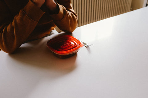 Person sat at a table with plastic tupperware container and fork.