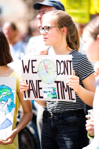 Young woman at a climate march holding a banner saying 'We Don't Have Time'/