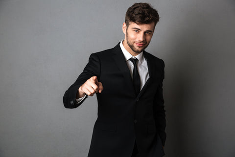 Young man in a tuxedo pointing his index finger at the camera