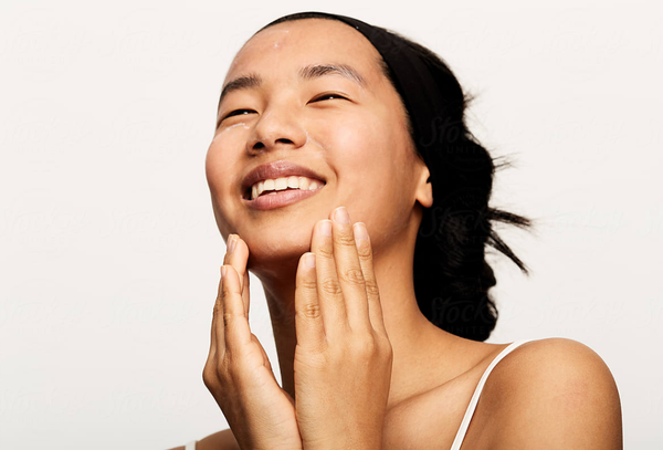 Young asian woman washing her face with hair tied back after microneedling treatment