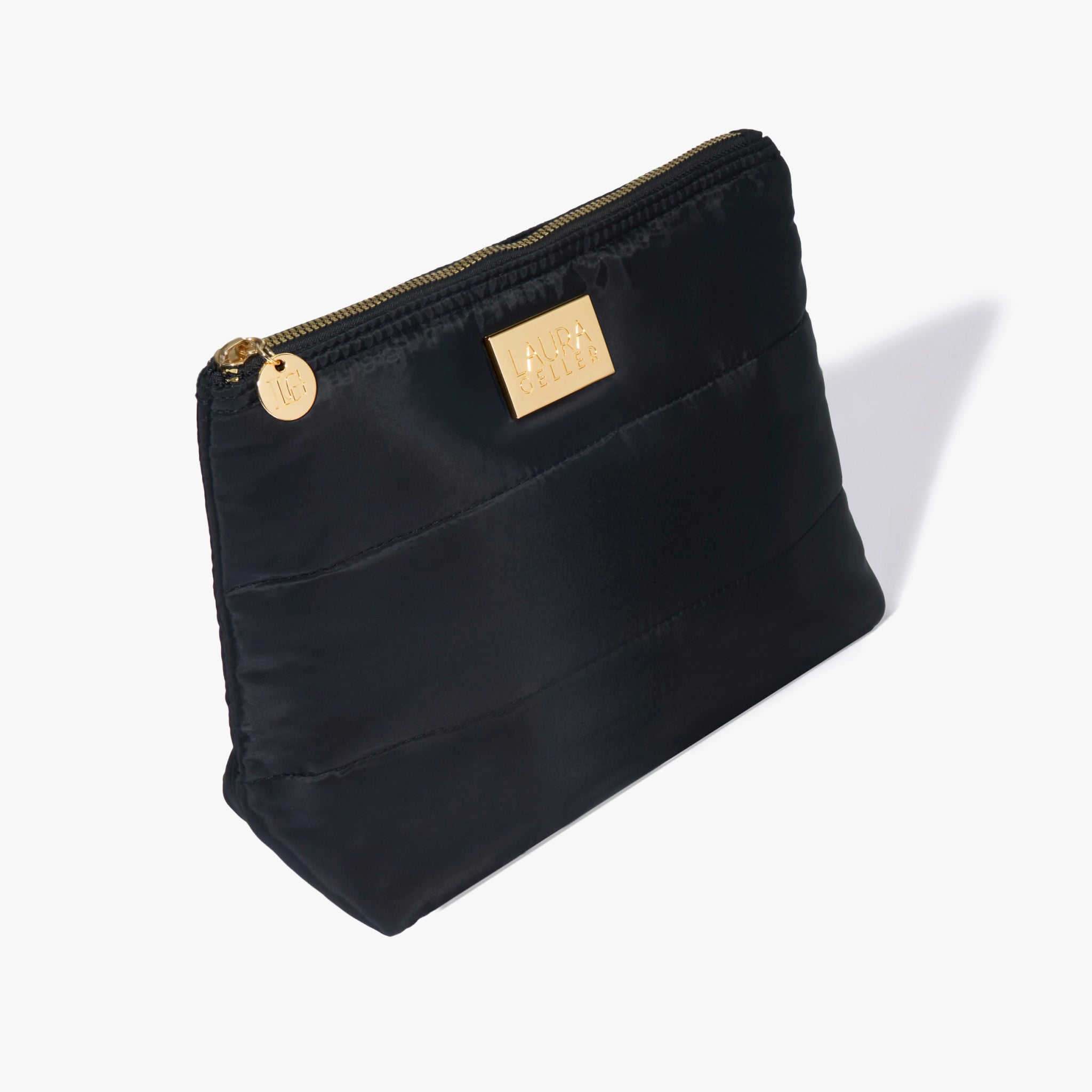 Black quilted pouch with gold zipper and a gold 'Laura Geller' logo plaque.