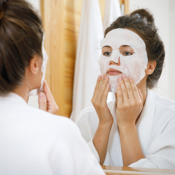 Woman with face mask looking in mirror