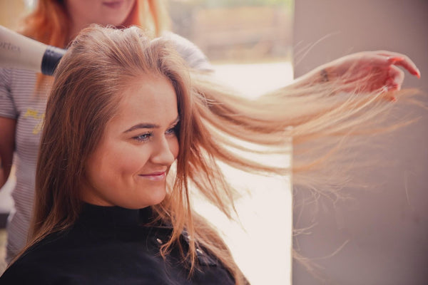 woman blow drying hair for volume on top