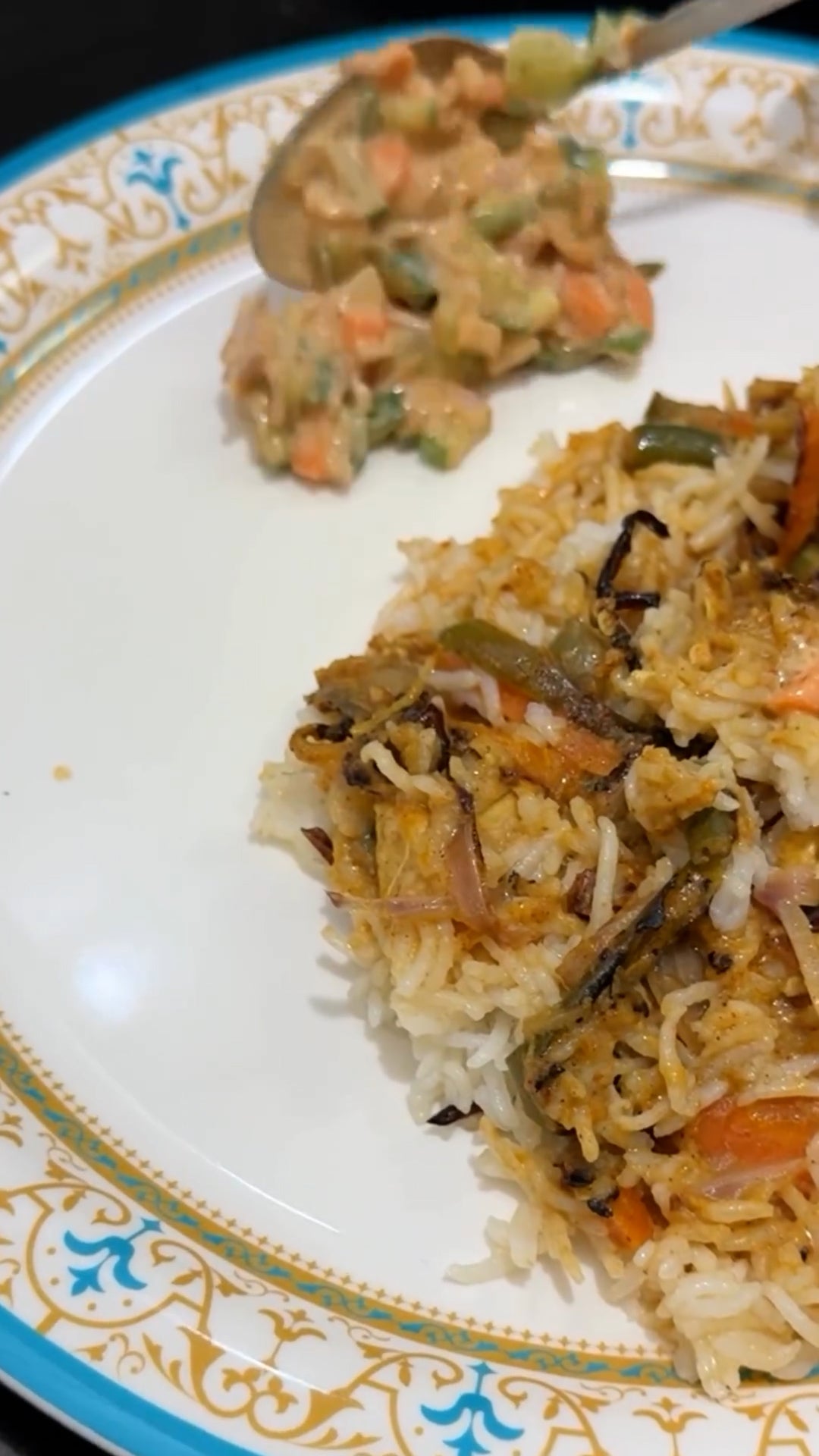 A plate of biryani rice with mixed vegetables and a side of creamy vegetable salad.