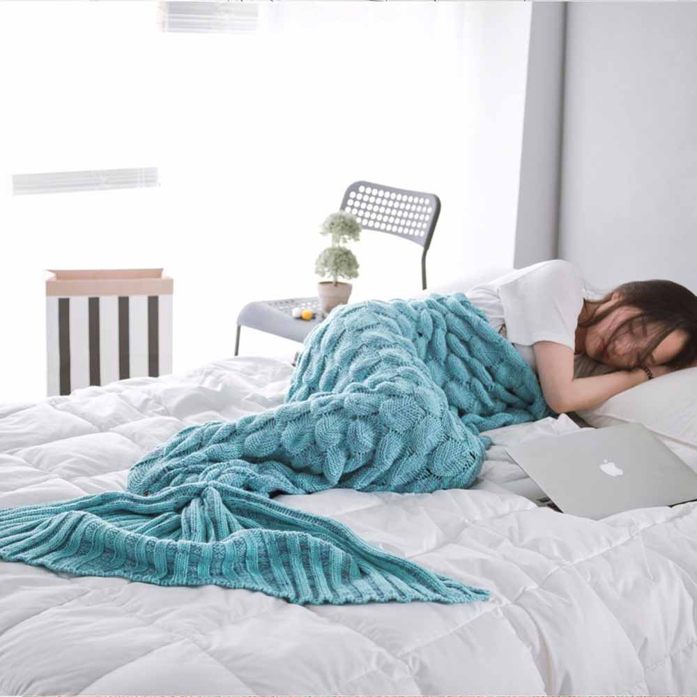 women in bed wearing a blue mermaid tail blanket