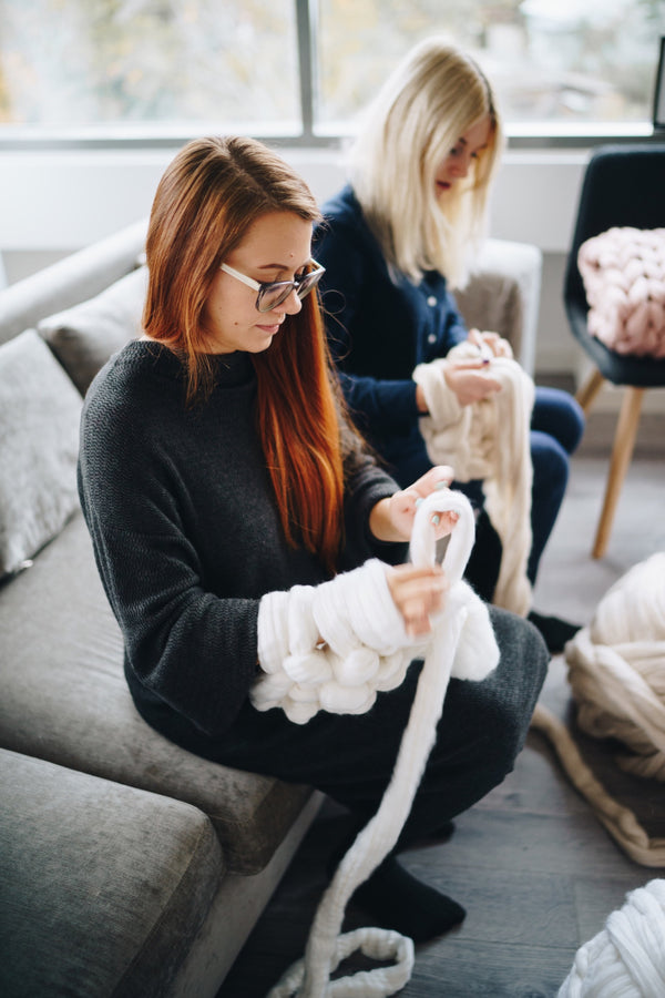 skein of giant merino pink yarn for arm knitting with large knitting needles  on a blue sofa Stock Photo