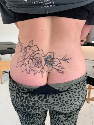 Selina Medina's tattoo coverup client, sun in the lower back covered up by the stencil of a rose and stem