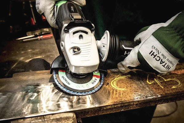 An angle grinder with a flap disc cleaning the metal.