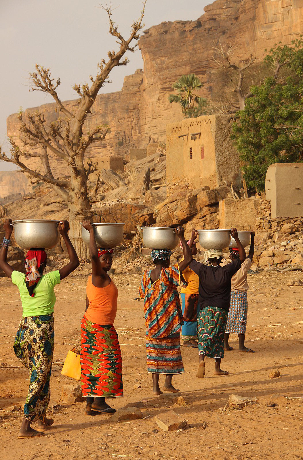 Safari Journal / Blog by Safari Fusion | Balancing act | Woman carrying pots in a Dogon Village Mali, West Africa | Photographer Raphael Bick
