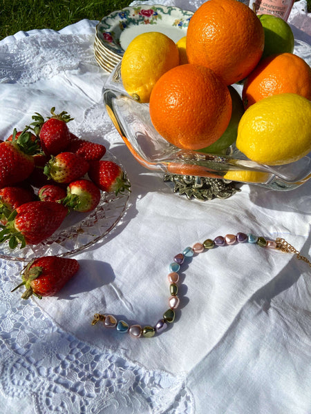 An anklet made of pastel coloured crystal pearls surrounded by fruit. 