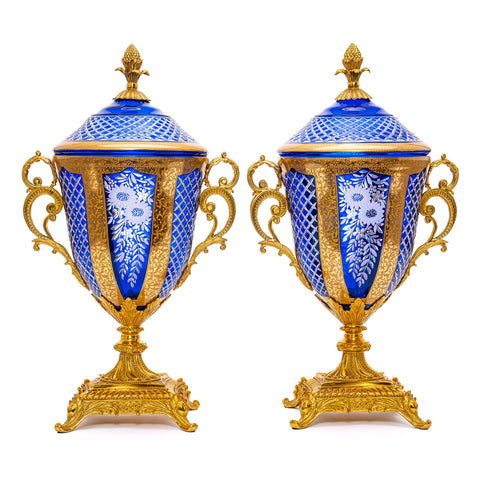 A stunning Cobalt Crystal Vase, resplendent in its deep blue hue. The intricate cut crystal floral motifs dance across its surface, shimmering as the light catches them, while doré bronze accents provide a striking contrast.