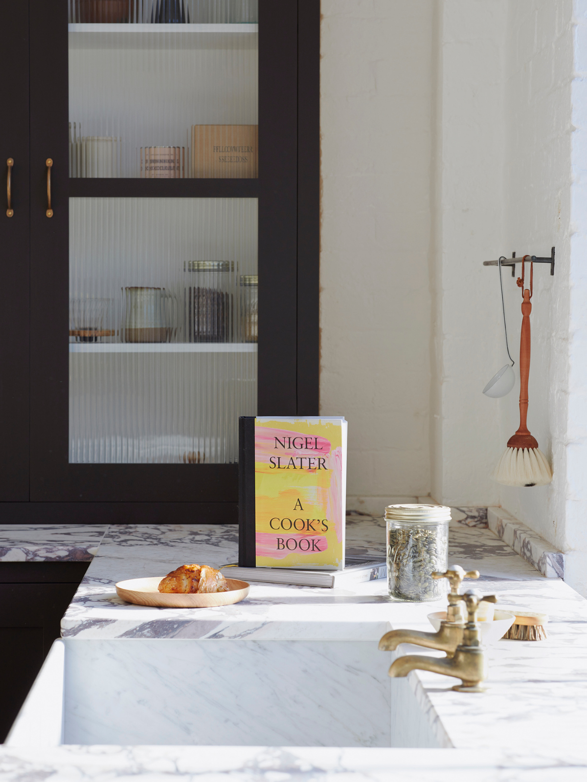 Nigel Slater's cookbook on a marble countertop in a rustic kitchen