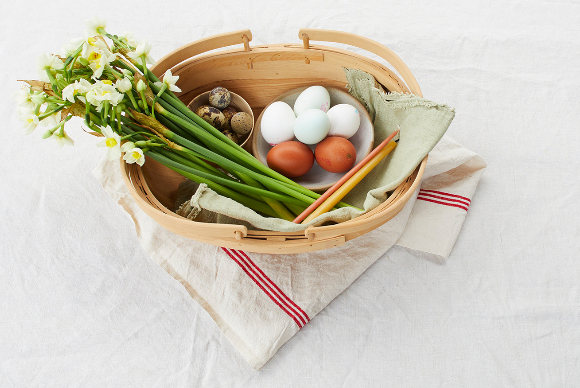 An Easter table with eggs and a bunch of spring daffodils in a basket