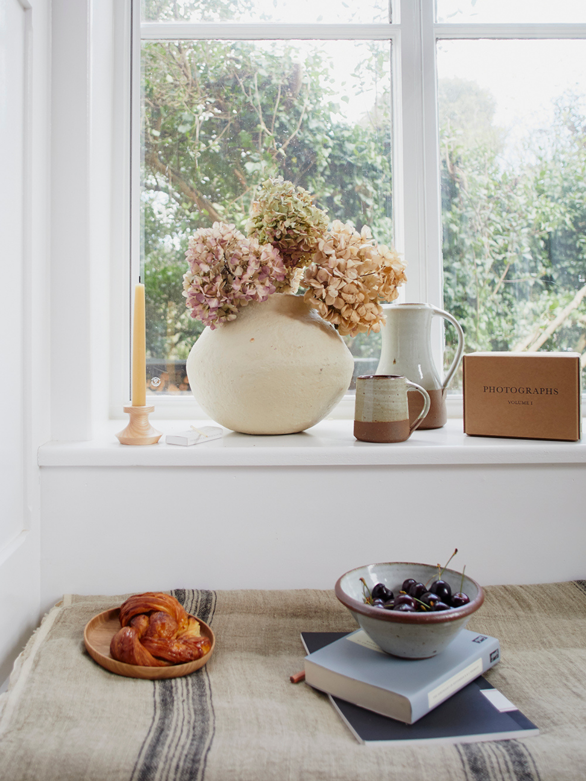 Books, flowers and a bowl of cherries on a window sill