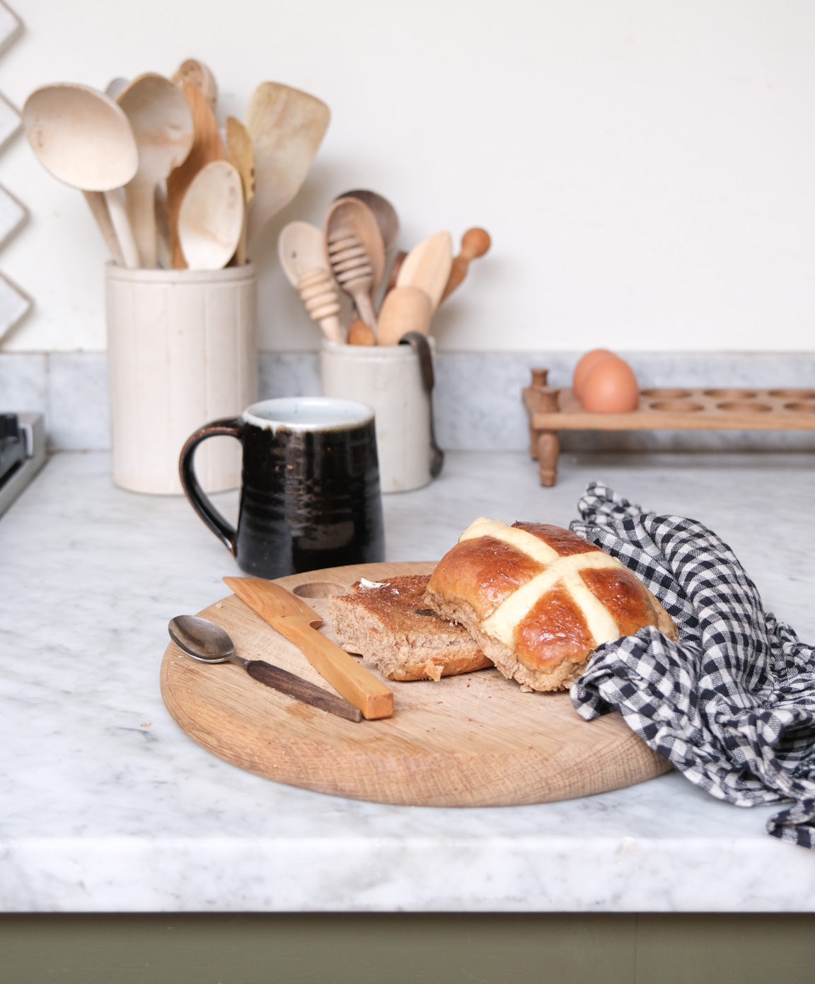 a kitchen counter with a cup of tea and a homemade hot cross bun